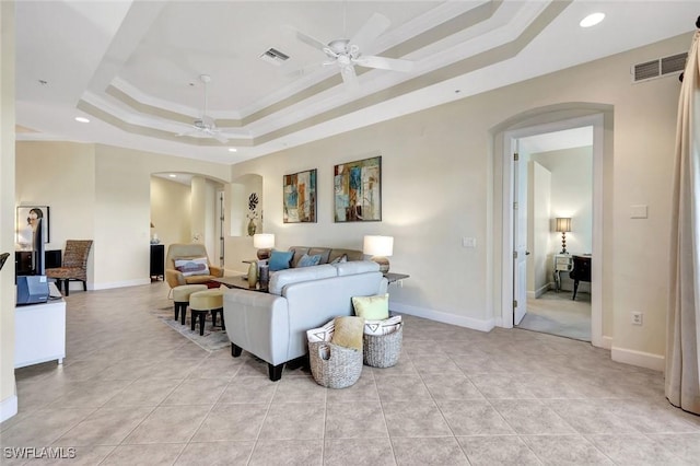 living area featuring visible vents, a ceiling fan, arched walkways, and a tray ceiling