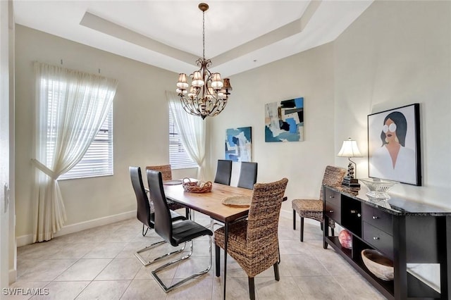 dining area with light tile patterned floors, a notable chandelier, and a raised ceiling