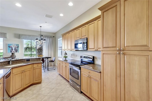 kitchen with light tile patterned floors, a sink, light brown cabinetry, stainless steel appliances, and a notable chandelier