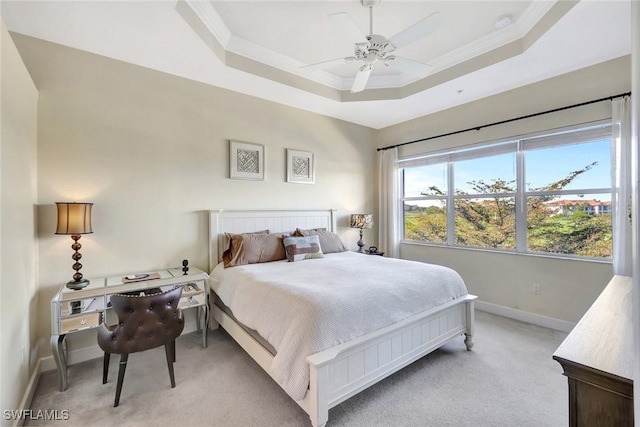 bedroom with a tray ceiling, light carpet, baseboards, and crown molding