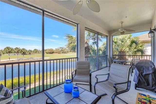 sunroom / solarium with a ceiling fan and a water view