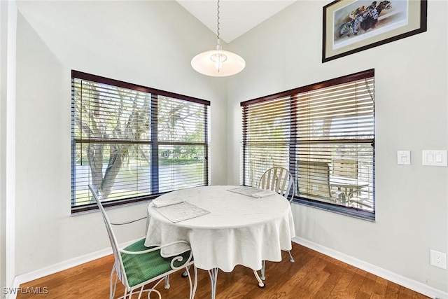 dining room with baseboards, wood finished floors, and vaulted ceiling