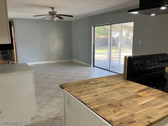 kitchen with electric range, range hood, light tile patterned floors, baseboards, and ceiling fan