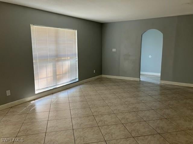 tiled empty room with arched walkways and baseboards