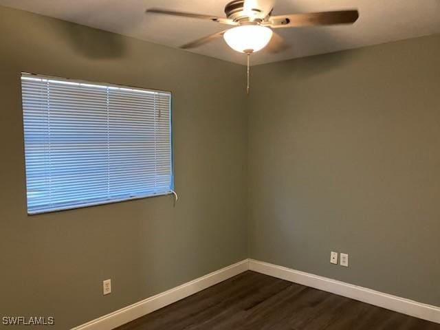 unfurnished room featuring dark wood finished floors, a ceiling fan, and baseboards