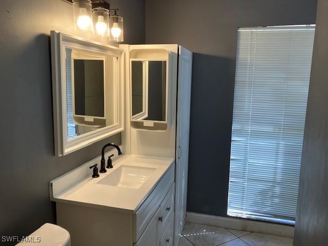 bathroom featuring tile patterned flooring, toilet, vanity, and baseboards