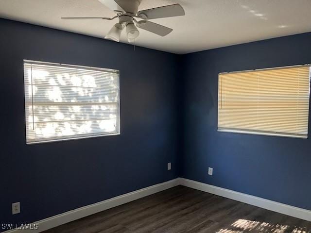 empty room with baseboards, dark wood-style flooring, and ceiling fan