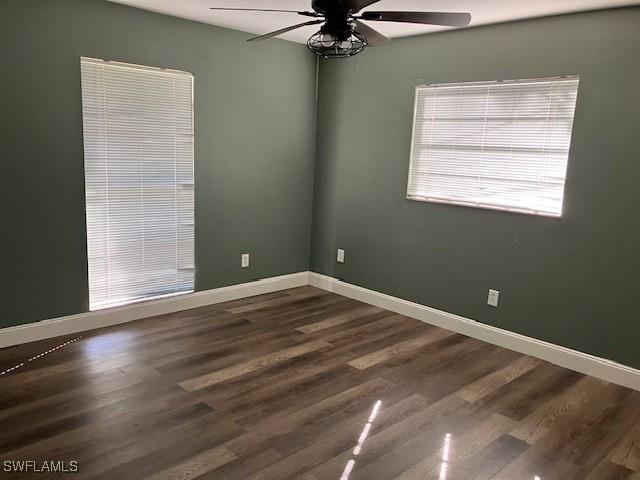 spare room with dark wood-style floors, ceiling fan, and baseboards