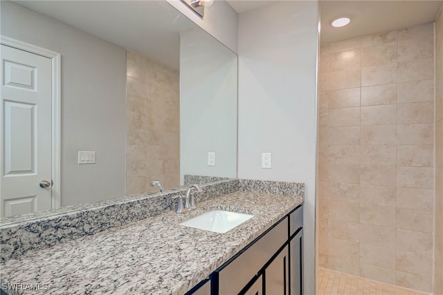 full bath featuring a tile shower and vanity