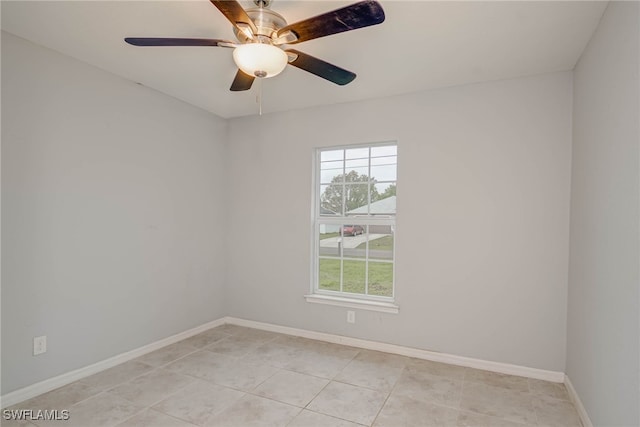 spare room featuring light tile patterned flooring, a ceiling fan, and baseboards