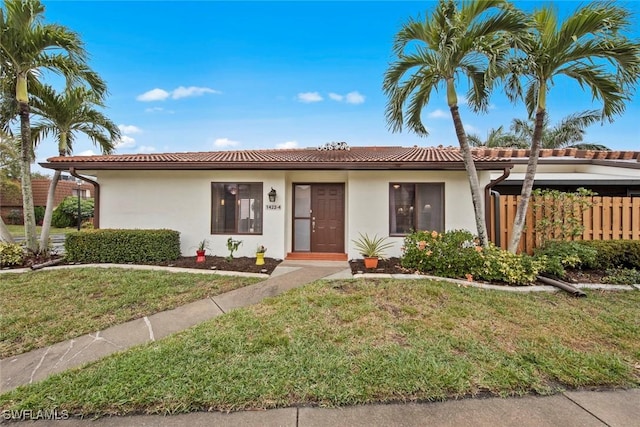 single story home featuring stucco siding, a front lawn, and a tiled roof