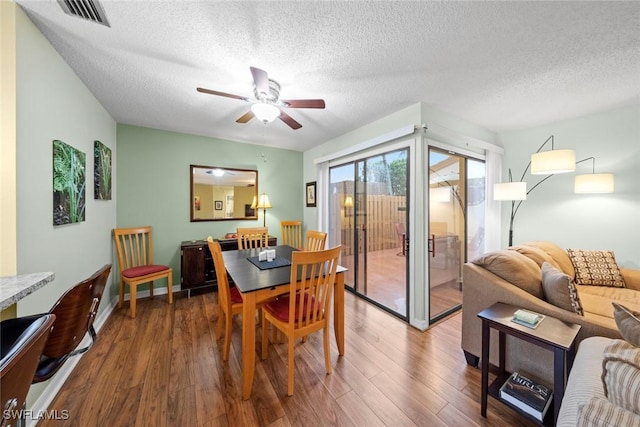 dining room featuring visible vents, baseboards, wood finished floors, a textured ceiling, and a ceiling fan