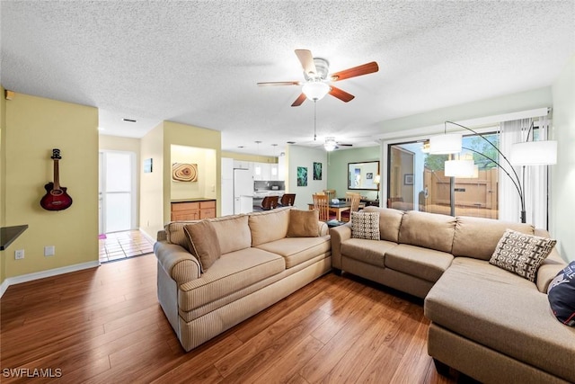 living room featuring baseboards, a textured ceiling, and wood finished floors