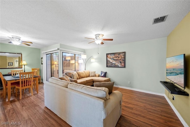 living area featuring a ceiling fan, wood finished floors, and visible vents