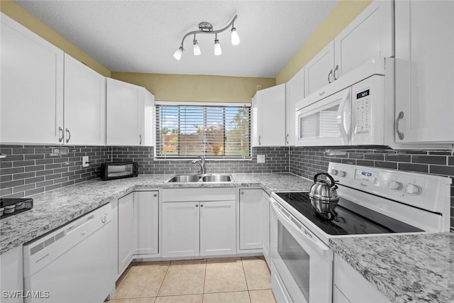 kitchen featuring light tile patterned floors, white appliances, white cabinetry, and a sink