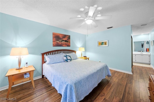 bedroom with visible vents, a textured ceiling, baseboards, and hardwood / wood-style flooring