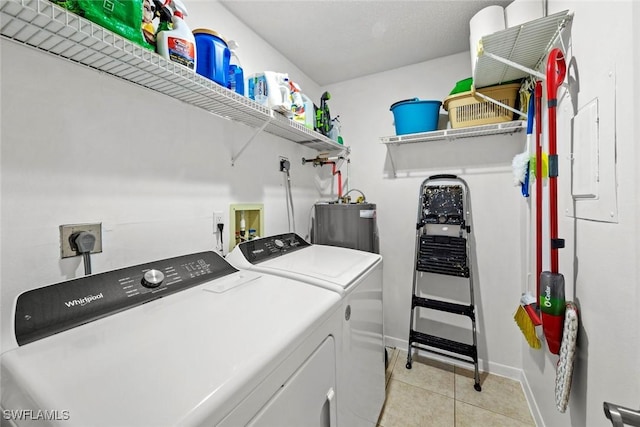 clothes washing area featuring light tile patterned floors, baseboards, washing machine and clothes dryer, laundry area, and electric water heater