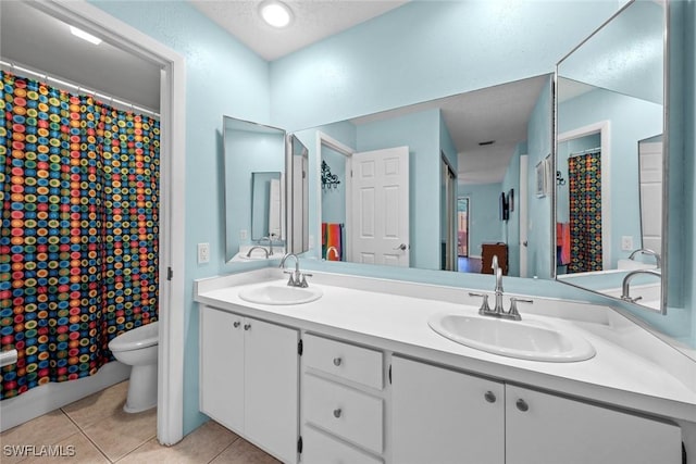 bathroom with tile patterned flooring, double vanity, toilet, and a sink