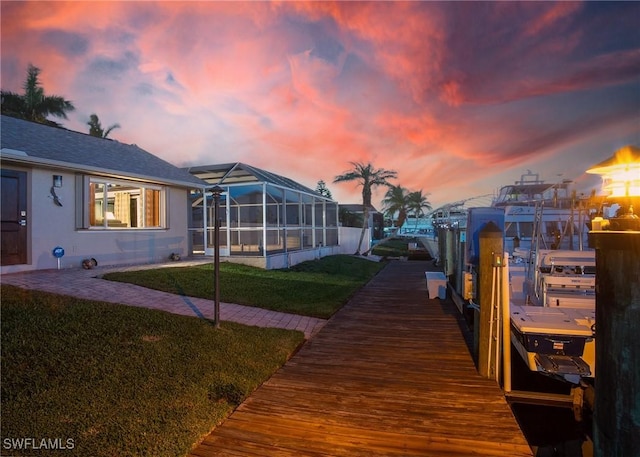 dock area with a lanai, a lawn, and boat lift