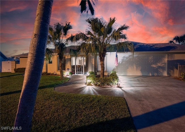 view of front facade featuring stucco siding, an attached garage, driveway, and a front yard