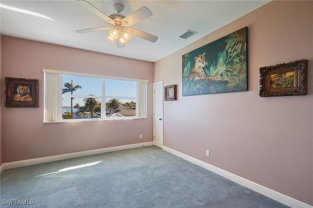 empty room featuring visible vents, carpet flooring, baseboards, and ceiling fan