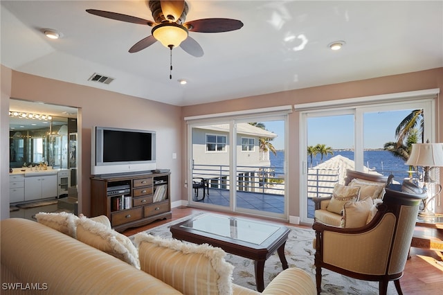 living area with visible vents, baseboards, wood finished floors, and a ceiling fan