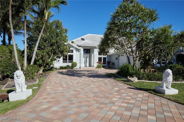 view of front of home featuring decorative driveway, stucco siding, an attached garage, and a tile roof