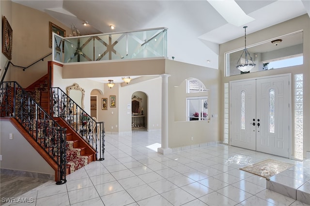 tiled entryway with a wealth of natural light, stairway, and a towering ceiling