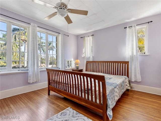 bedroom with baseboards, wood-type flooring, and ceiling fan