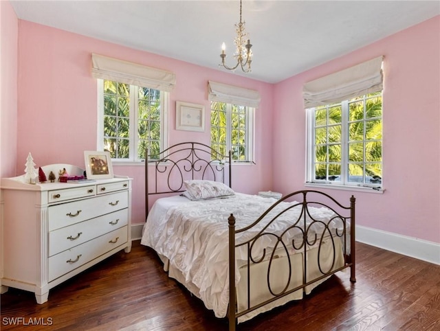 bedroom with a notable chandelier, dark wood-style floors, and baseboards