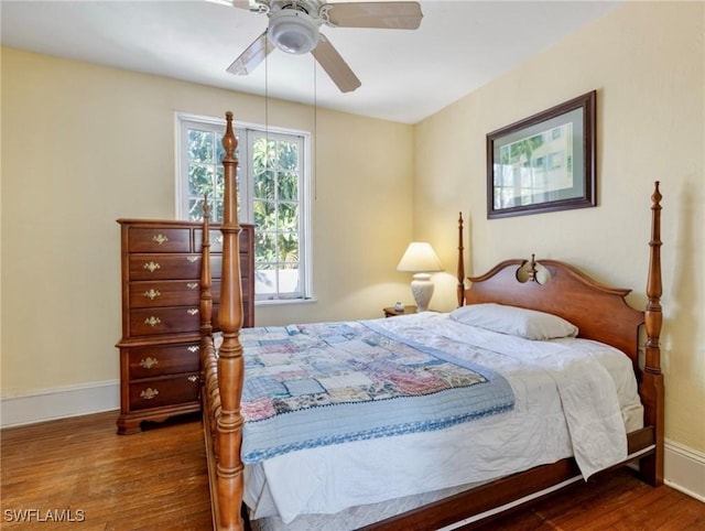 bedroom with a ceiling fan, wood finished floors, and baseboards