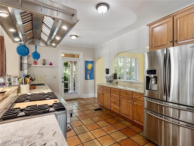 kitchen with light countertops, island range hood, arched walkways, stainless steel appliances, and a sink