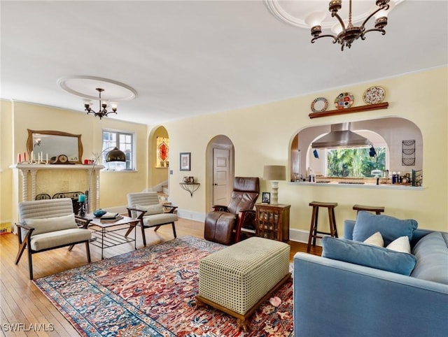 living area with arched walkways, a notable chandelier, baseboards, and wood-type flooring