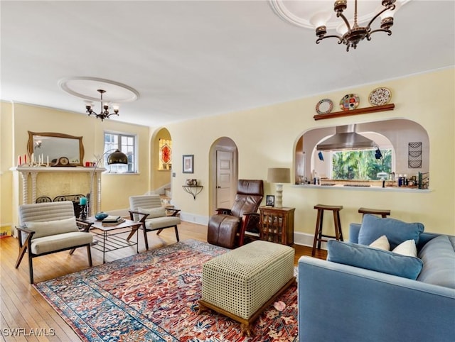 living area with baseboards, arched walkways, a notable chandelier, and hardwood / wood-style floors