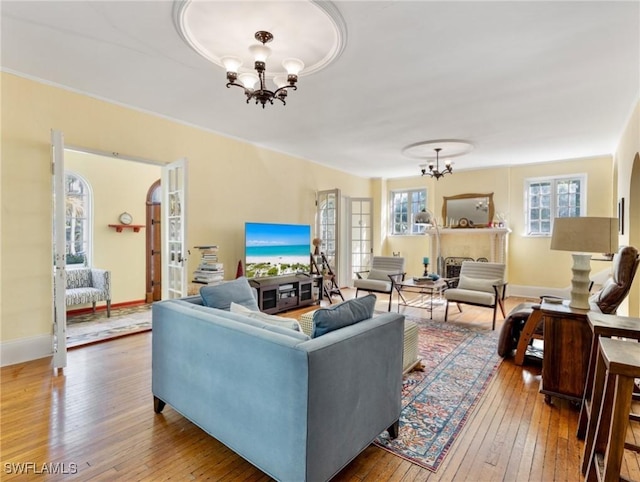 living area featuring hardwood / wood-style flooring, baseboards, and a chandelier