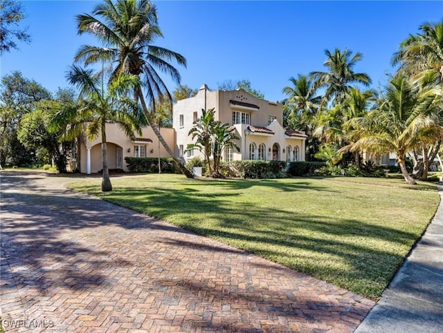 mediterranean / spanish-style home with a front yard, decorative driveway, and stucco siding