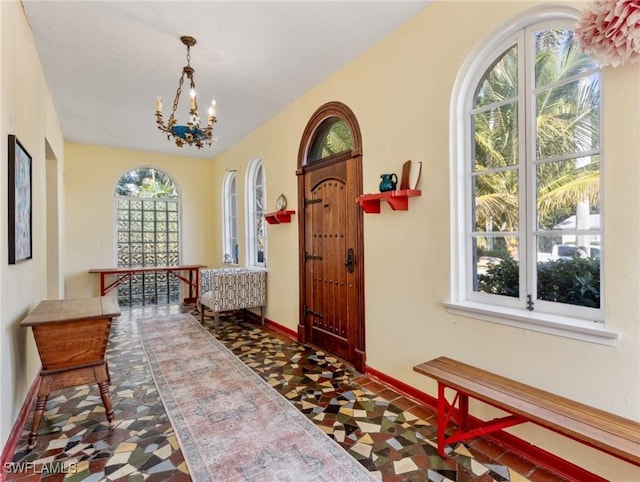 foyer entrance with a notable chandelier and baseboards