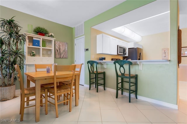 dining space featuring light tile patterned floors, visible vents, and baseboards