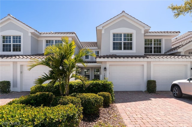 view of front of house featuring decorative driveway, a garage, and stucco siding