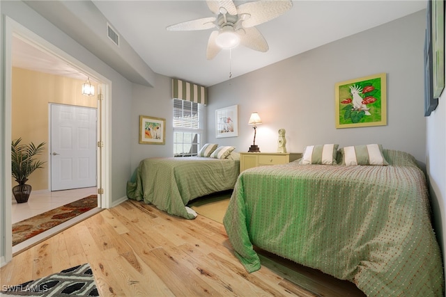 bedroom featuring visible vents, baseboards, a ceiling fan, and wood finished floors