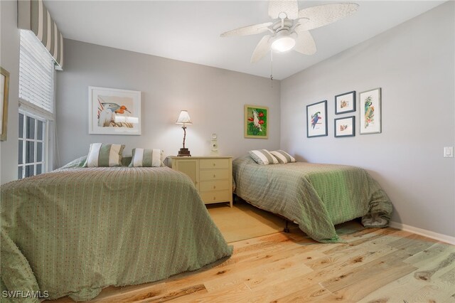 bedroom featuring baseboards, light wood-style floors, and a ceiling fan