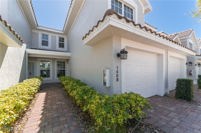 view of home's exterior featuring stucco siding, a tiled roof, and a garage