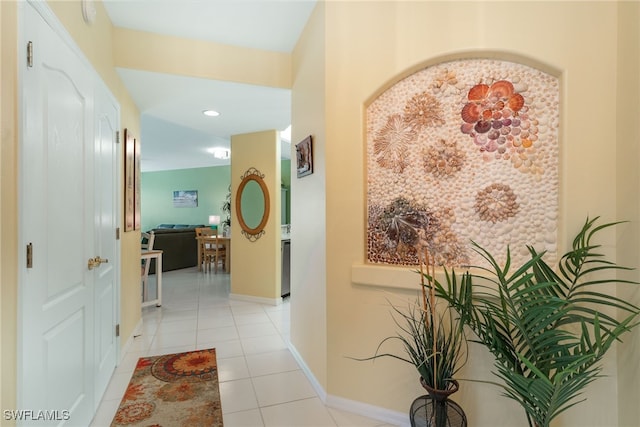 corridor featuring light tile patterned floors and baseboards