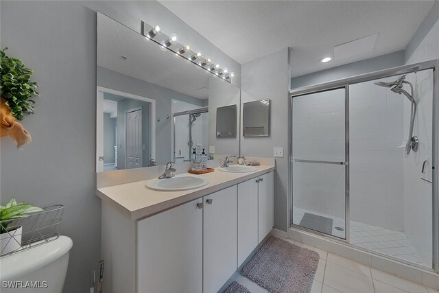 bathroom with a shower stall, tile patterned floors, toilet, and a sink
