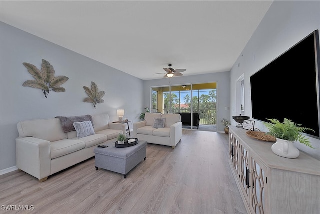 living area with baseboards, light wood-type flooring, and a ceiling fan