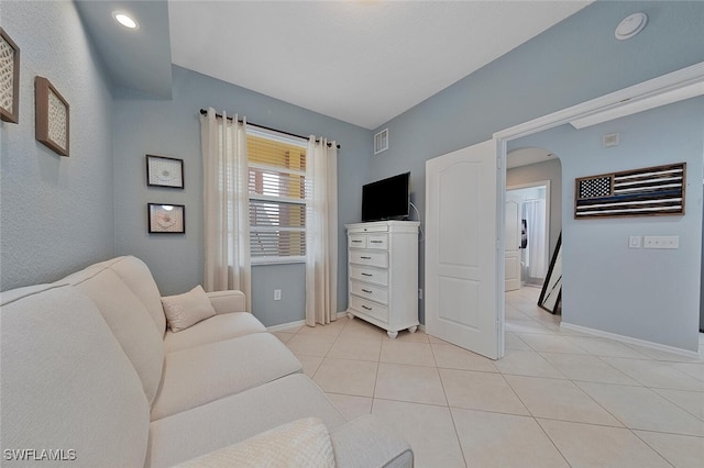 living area featuring arched walkways, baseboards, visible vents, and light tile patterned floors
