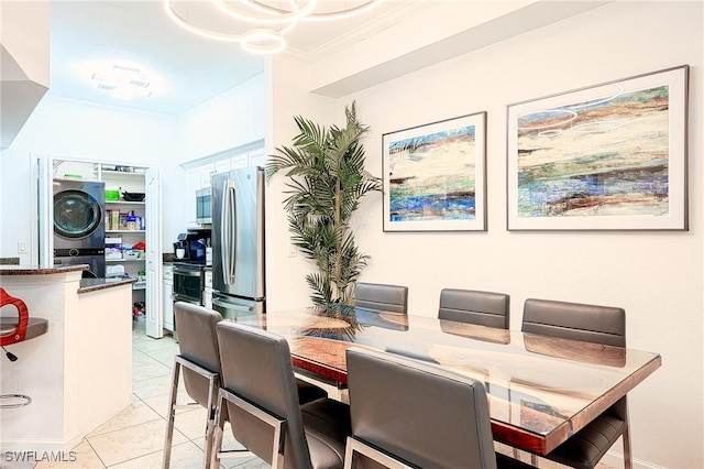 dining room with light tile patterned floors, stacked washer and dryer, and ornamental molding