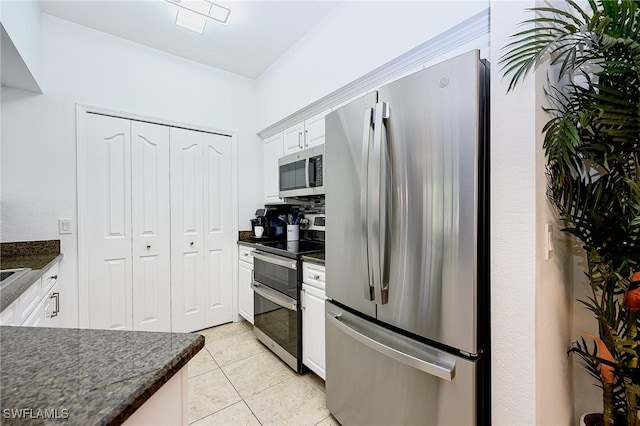 kitchen with white cabinetry, dark countertops, light tile patterned flooring, and appliances with stainless steel finishes