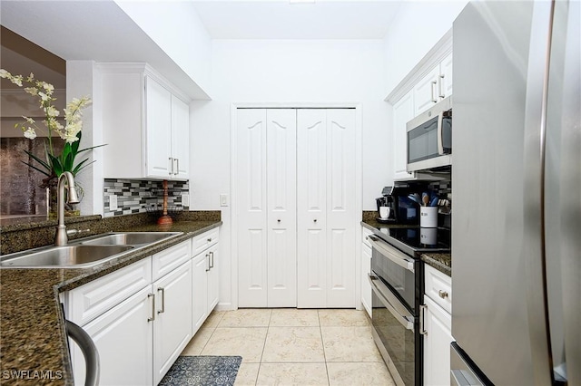 kitchen with light tile patterned flooring, a sink, white cabinets, appliances with stainless steel finishes, and tasteful backsplash