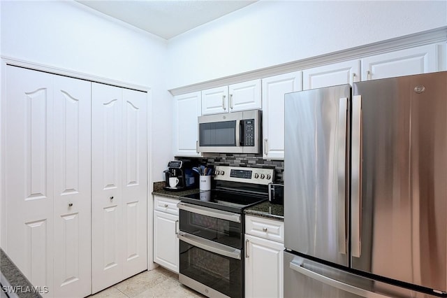 kitchen featuring decorative backsplash, dark stone countertops, white cabinetry, and appliances with stainless steel finishes